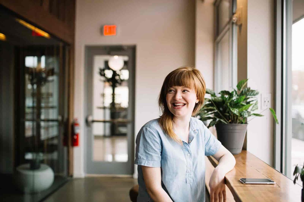 Smiling woman sat inside a cafe, by the window