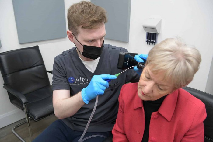 Audiologist completing microsuction ear wax removal with a female customer