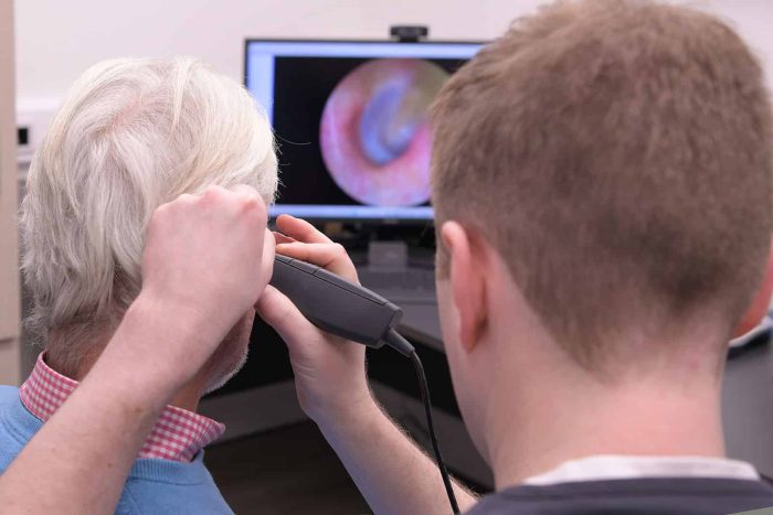 A private audiologist examining a patient’s ear health during an ear wax removal consultation.