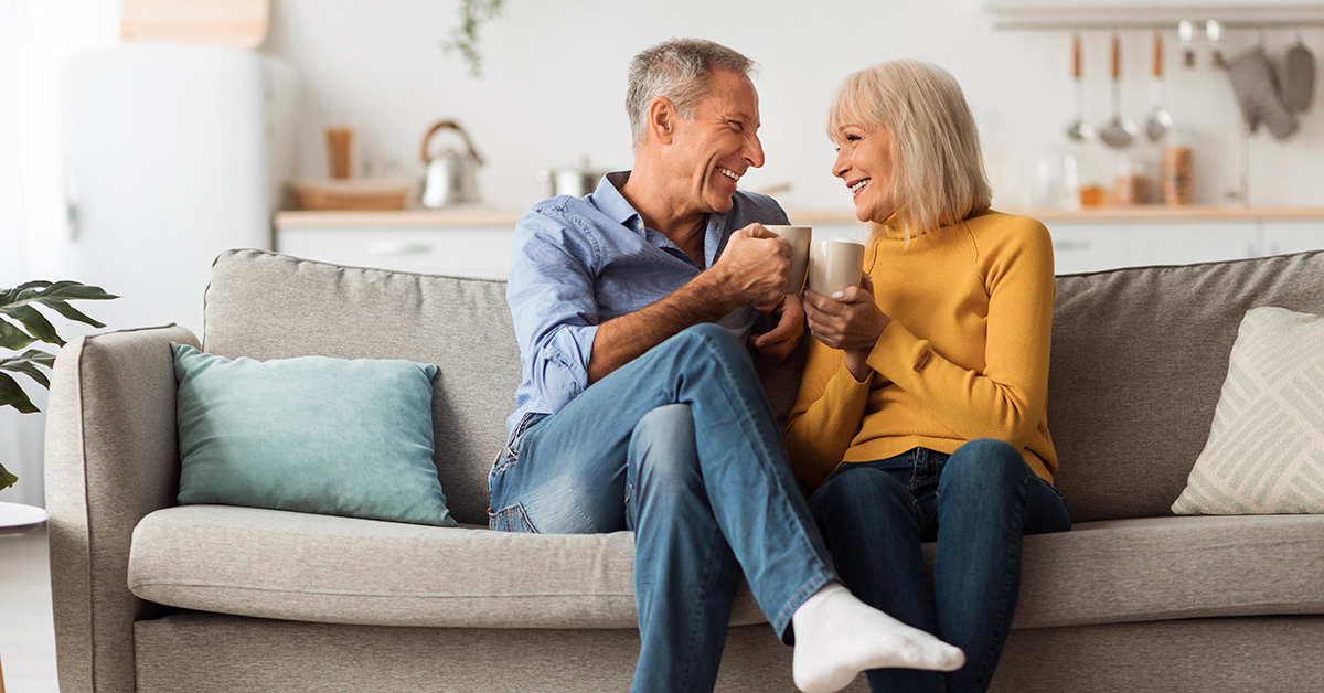 Couple sharing tea on sofa.