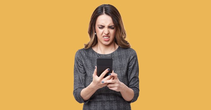Lady with brown hair looking at phone with disgusted look on her face as if watching ear wax removal.