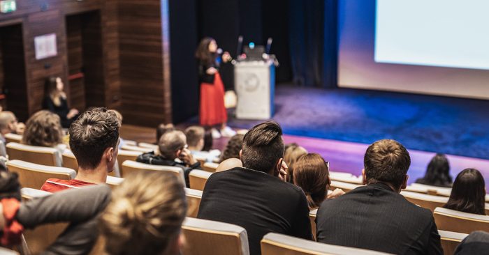 Where auracast could be used: woman speaking into a microphone at a lecture