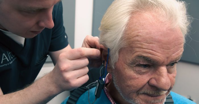 Audiologist inserting real ear measurements probe tube into ear
