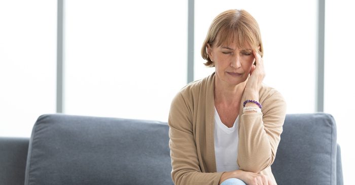Hearing aid insurance: image of lady frustrated after losing one of her hearing aids