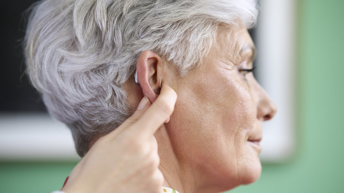 CROS hearing aid being fitted behind the ear