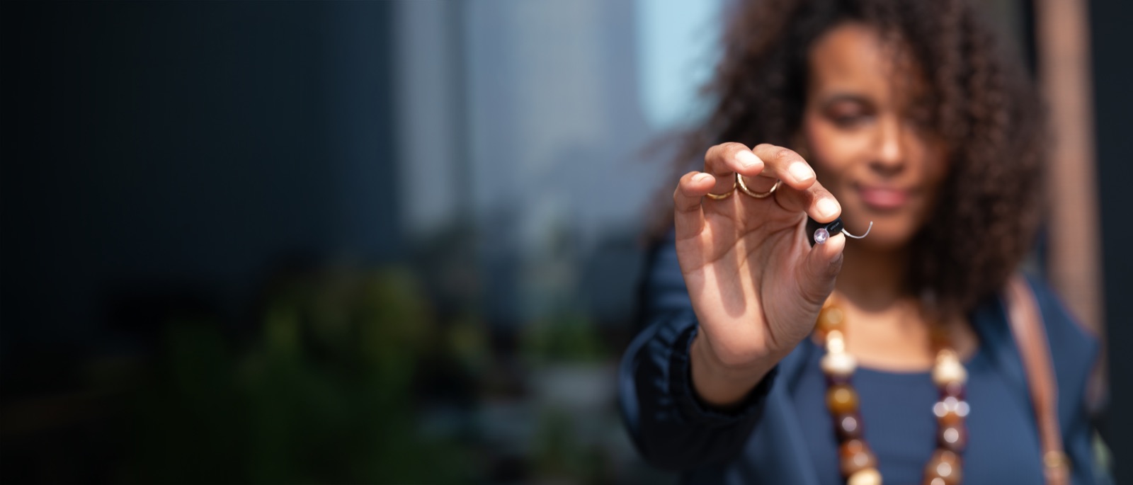 Person holding an Oticon Zeal in-ear hearing aid