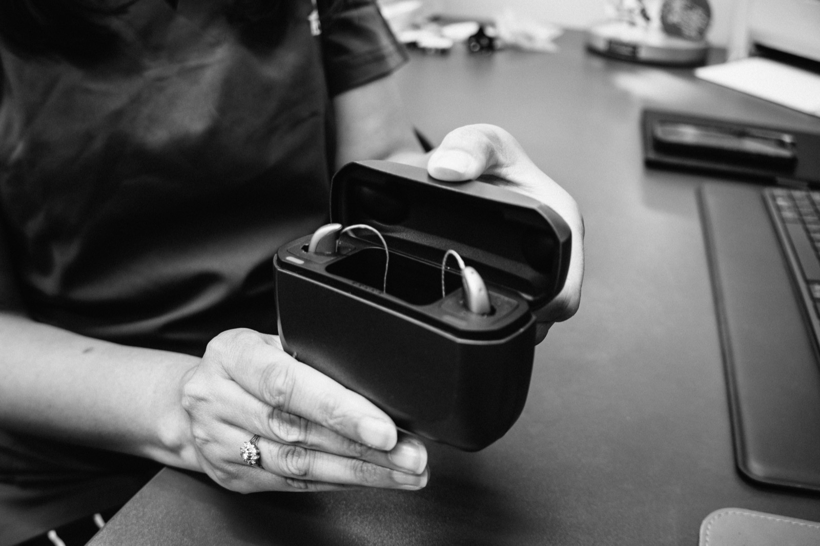 An Alto team member holding an open charger containing two hearing aids