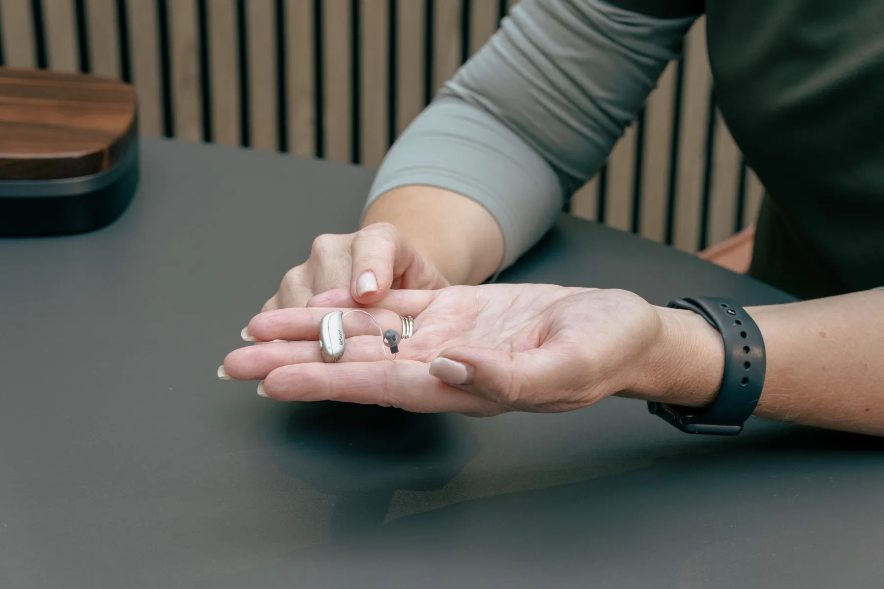 Receiver-in-canal hearing aid resting in a hand at Alto